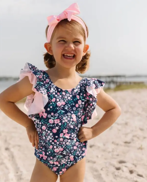 Soft, sweet flowers adorn a bold background on this blue floral flutter sleeve swimsuit for girls. Made from a fabric with UPF 50+ sun protection built in and feat
