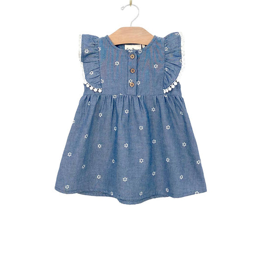 Made with 100% light chambray cotton. This charming baby dress features adorable flutter sleeves with pinafore detailing, coconut buttons in the front, and a soft el